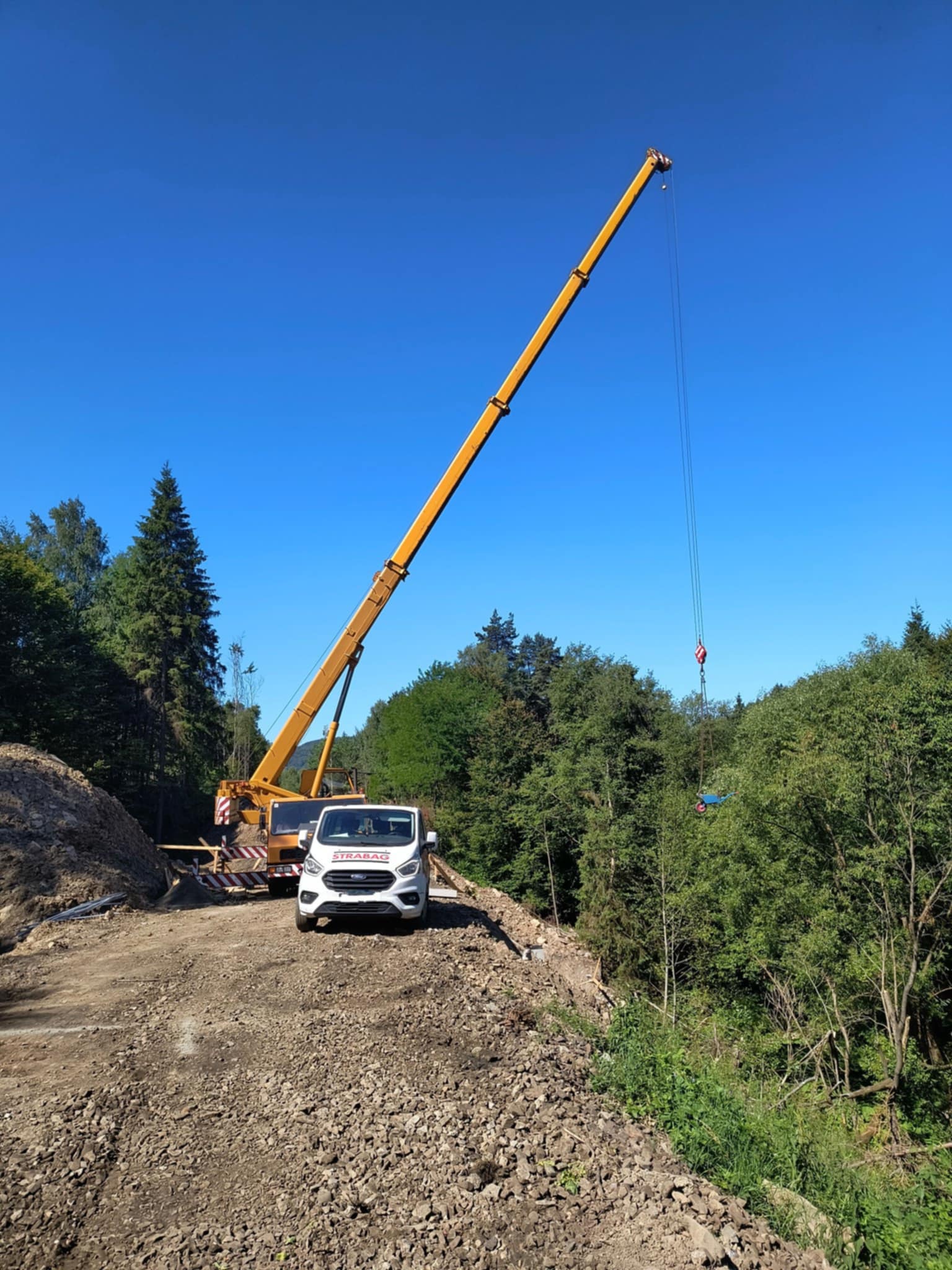 Dźwig podnoszący betonowy blok na placu budowy