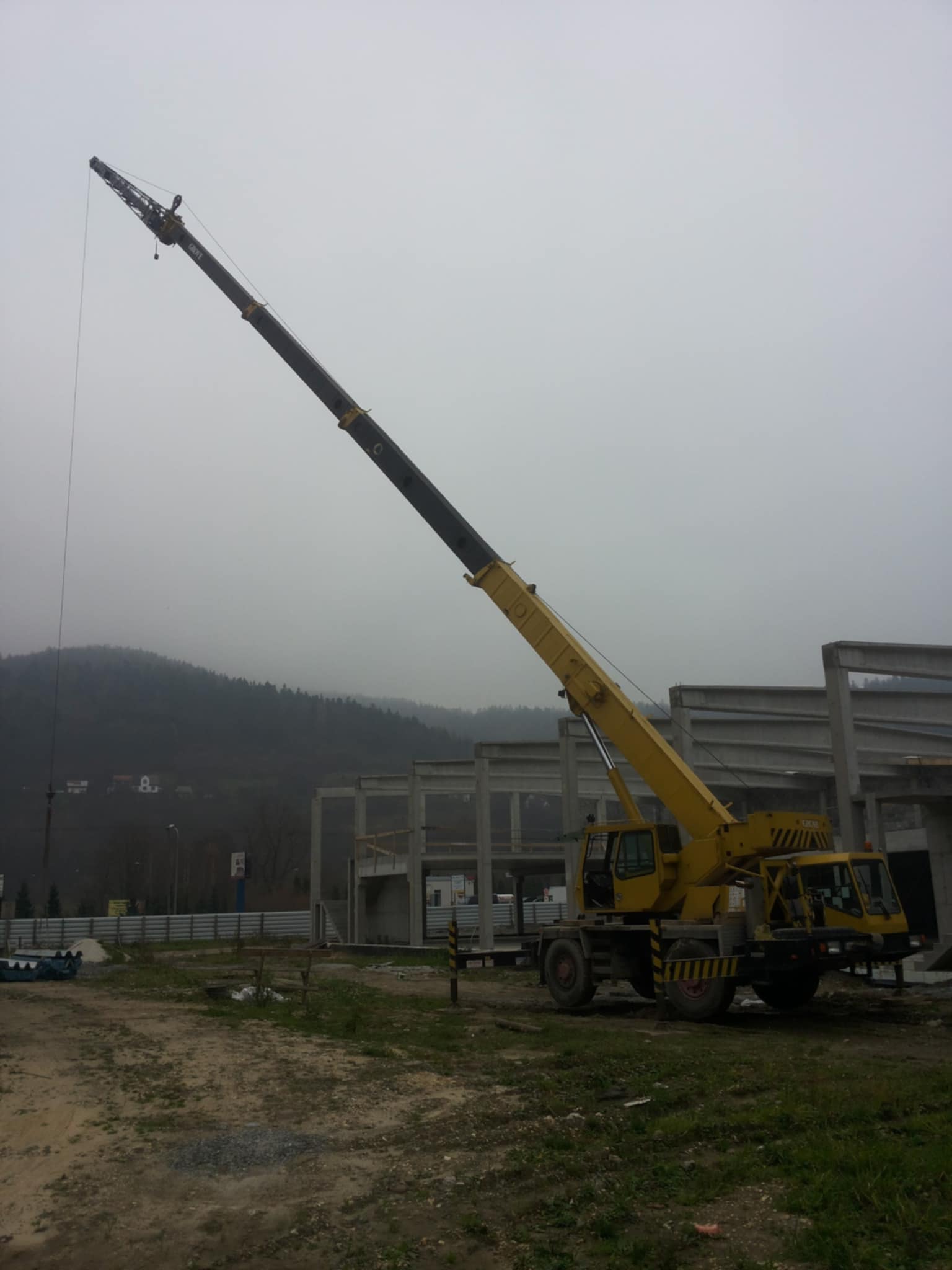 Dźwig na tle konstrukcji betonowej w mglisty dzień